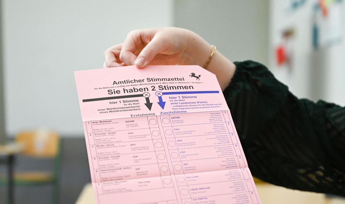 Eine Wahlhelferin in einem Stuttgarter Wahllokal zeigt den Stimmzettel.