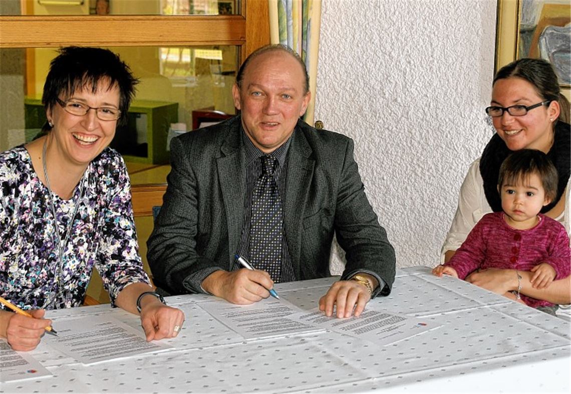 Einen Kooperationsvertrag zur sowohl flexiblen wie auch verlässlichen Kinderbetreuung im Mehrgenerationenhaus in Mühlacker unterzeichnen dessen Leiterin Alexandra Rapp und Werner Kunstetter vom Tagesmütterverein Enztal. Betreuerin Denise Burkhard (re.) und die kleine Josefina verfolgen aufmerksam das Geschehen. Foto: Kollros