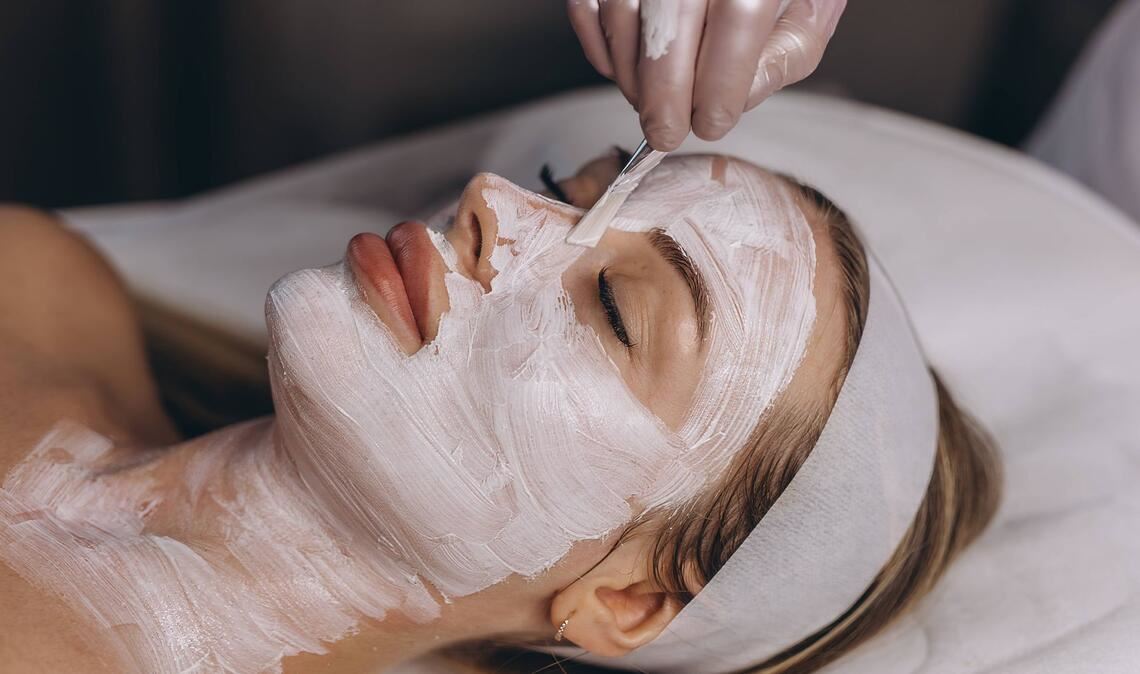 Einer Frau wird in einem Kosmetikstudio eine Gesichtsmake aufgetragen.