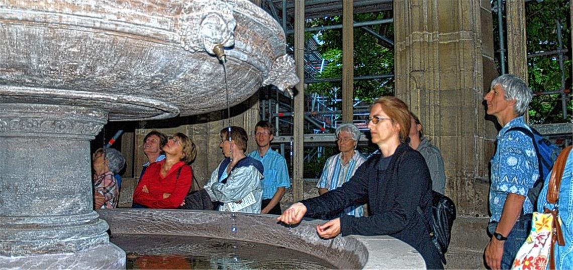 Einige bewundern die Rötelzeichnung an der gewölbten Decke des Brunnenhauses, andere lädt das Rinnen des Wassers zu einer Meditation ein.