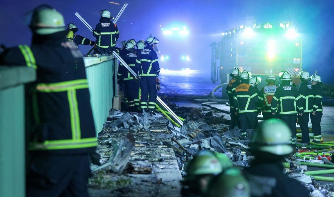 Einsatzkräfte der Feuerwehr sind dabei einen Brand in einem Industriegebiet im Hamburger Hafen zu löschen.