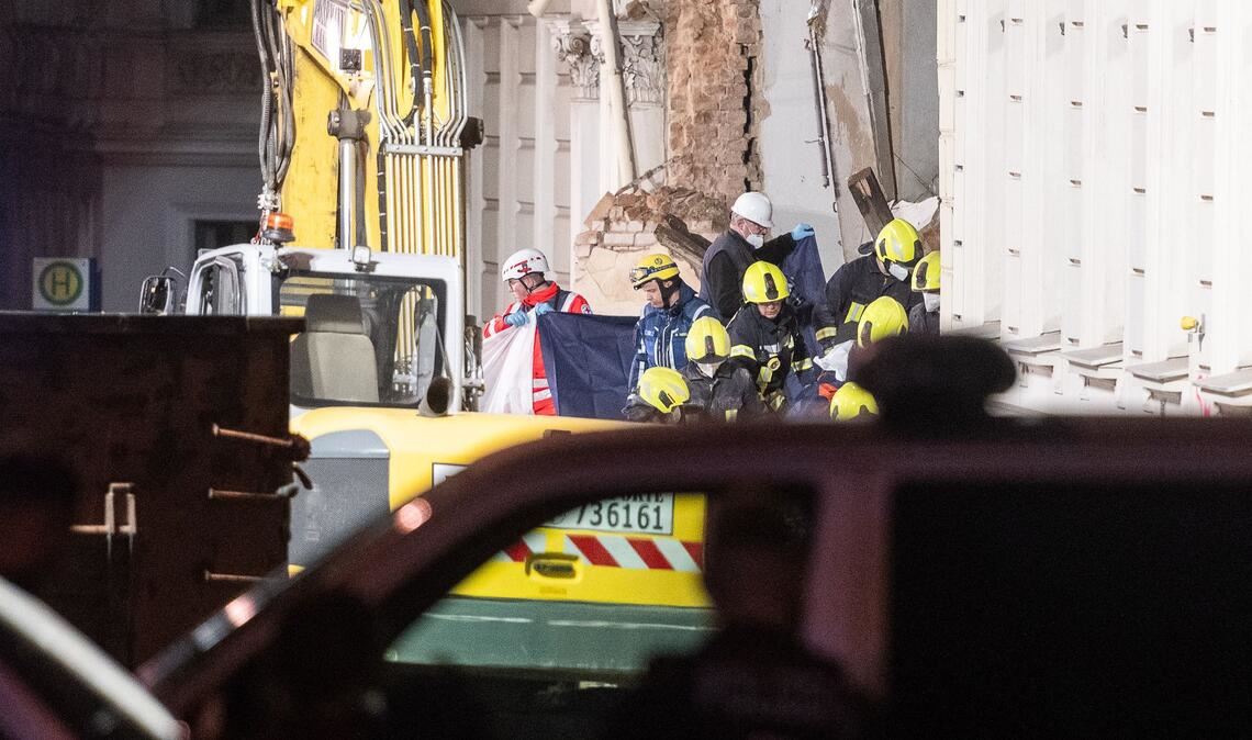 Einsatzkräfte der Feuerwehr tragen hinter Sichtschutz eine Leiche aus dem Trümmerfeld eines eingestürzten Hauses in Görlitz.