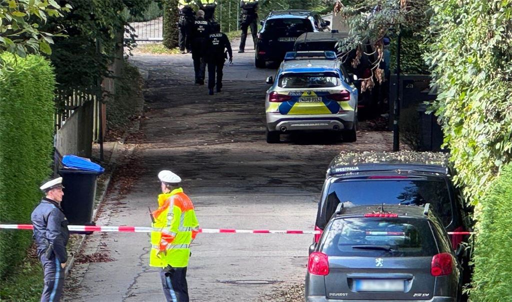 Einsatzkräfte der Polizei stehen bei einer Durchsuchung in einer Straße. Die Polizei geht bei einem Großbrand mit Explosionen im Münchner Norden derzeit von einem privaten Hintergrund aus.