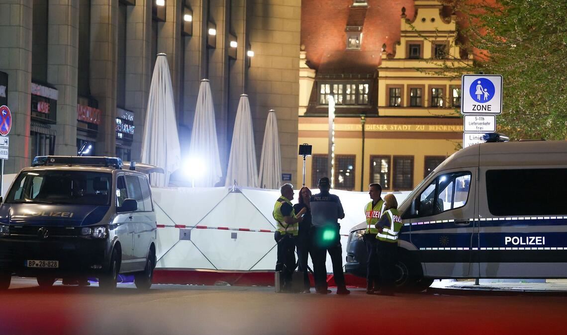 Einsatzkräfte stehen neben dem Sichtschutz vor dem Tatfahrzeug in der Grimmaischen Straße. In Leipzig ist ein Auto in mehrere Menschen gefahren.