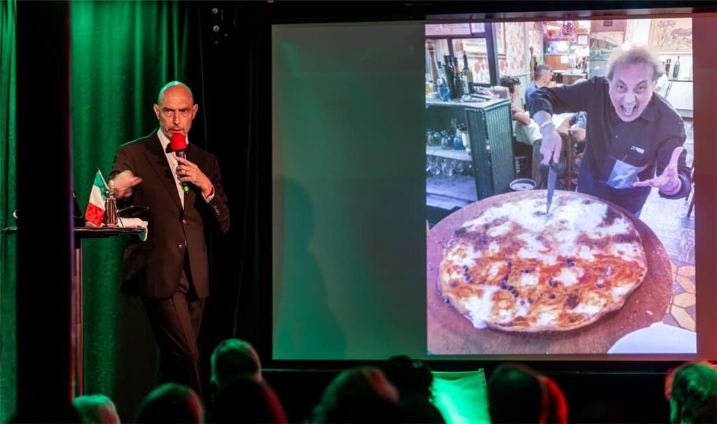 Eric Pfeil liest im Stuttgarter Kulturzentrum Merlin aus seinem Buch „Hotel Celentano“ und zeigt dabei ein Bild von riesigen Pizzen. Foto: Lichtgut/Christoph Schmidt