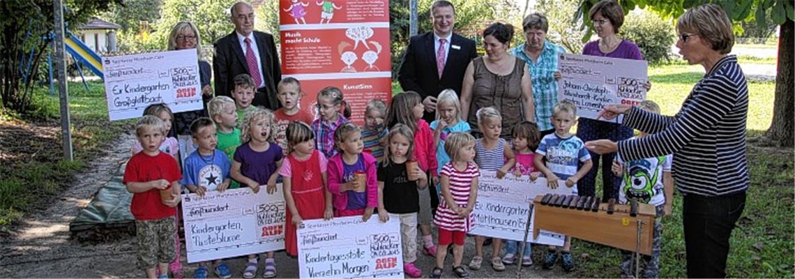 Erzieherin Silvia Krauss (hinten v.li.), ObenAuf-Geschäftsführer Helmut Wagner, Marktdirektor Gerd Owczarek, die Leiterin des evangelischen Kindergartens Mühlhausen, Eva-Marie Schlotterbeck, Ingrid Giller, Leiterin des Johann-Christoph-Blumhardt-Kindergartens in Lomersheim, und Kantorin Susanne Schmidt-Zahnlecker freuen sich mit den Kindern über die Spende.