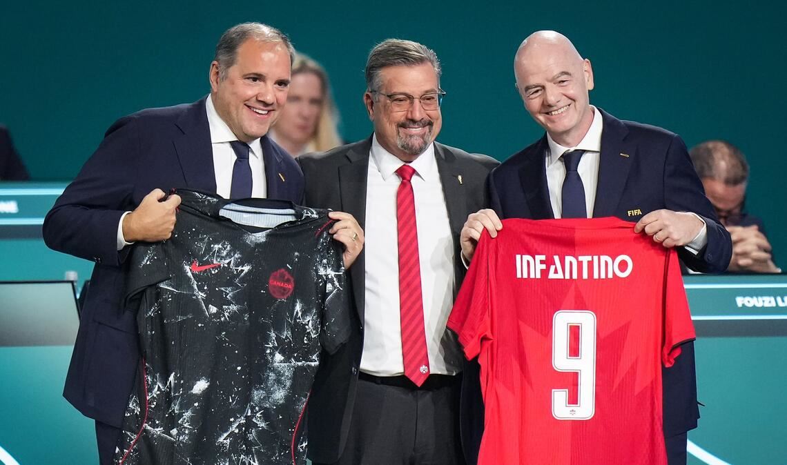 FIFA-Präsident Gianni Infantino (r) präsentiert mit Vizepräsident Victor Montagliani (l) und Kanadas Fußballchef Peter Augruso ein kanadisches Nationaltrikot mit seinem Namen.