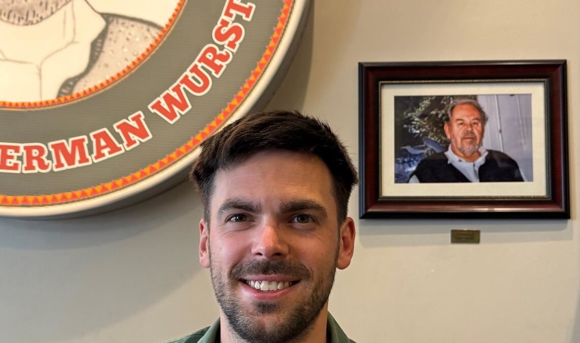 Fabian Förster steht vor einem Foto seines Großvaters, nach dem "Dieters Grill" benannt wurde.