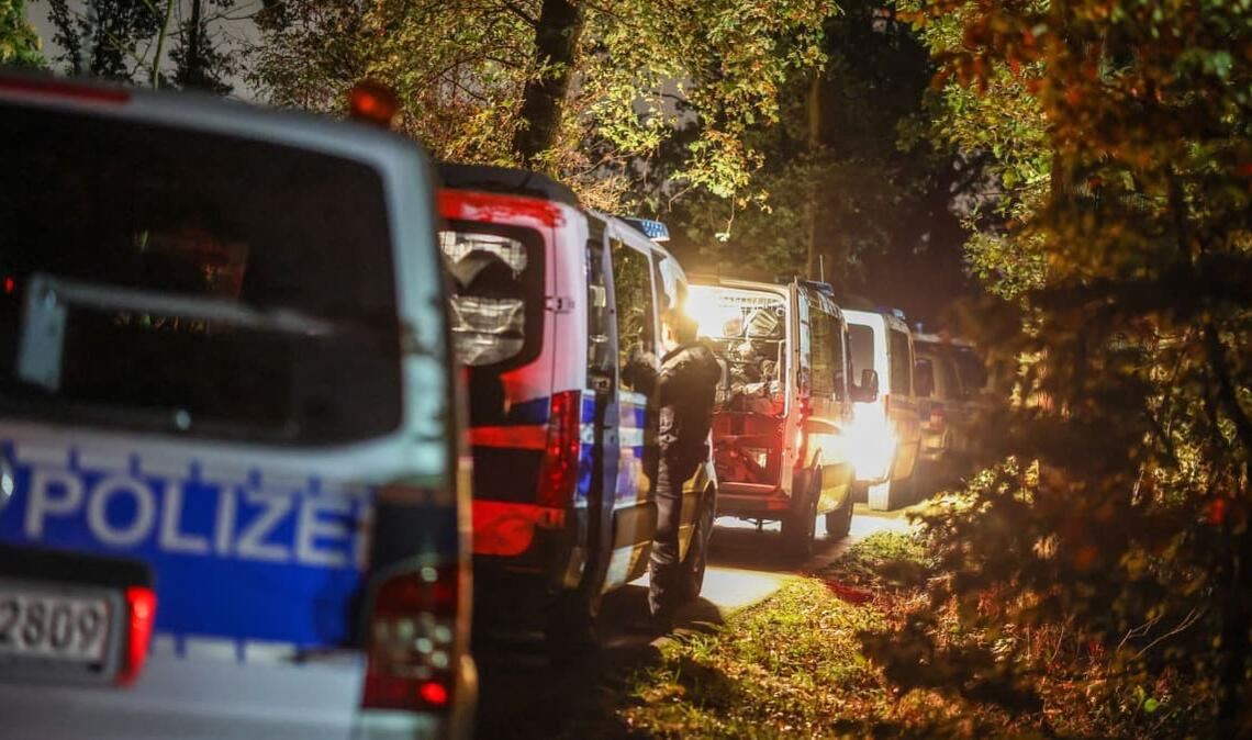 Fahrzeuge einer Einsatzhundertschaft der Polizei stehen in einem Waldgebiet in der Nähe des aufgefundenen Lastwagens des Tatverdächtigen.