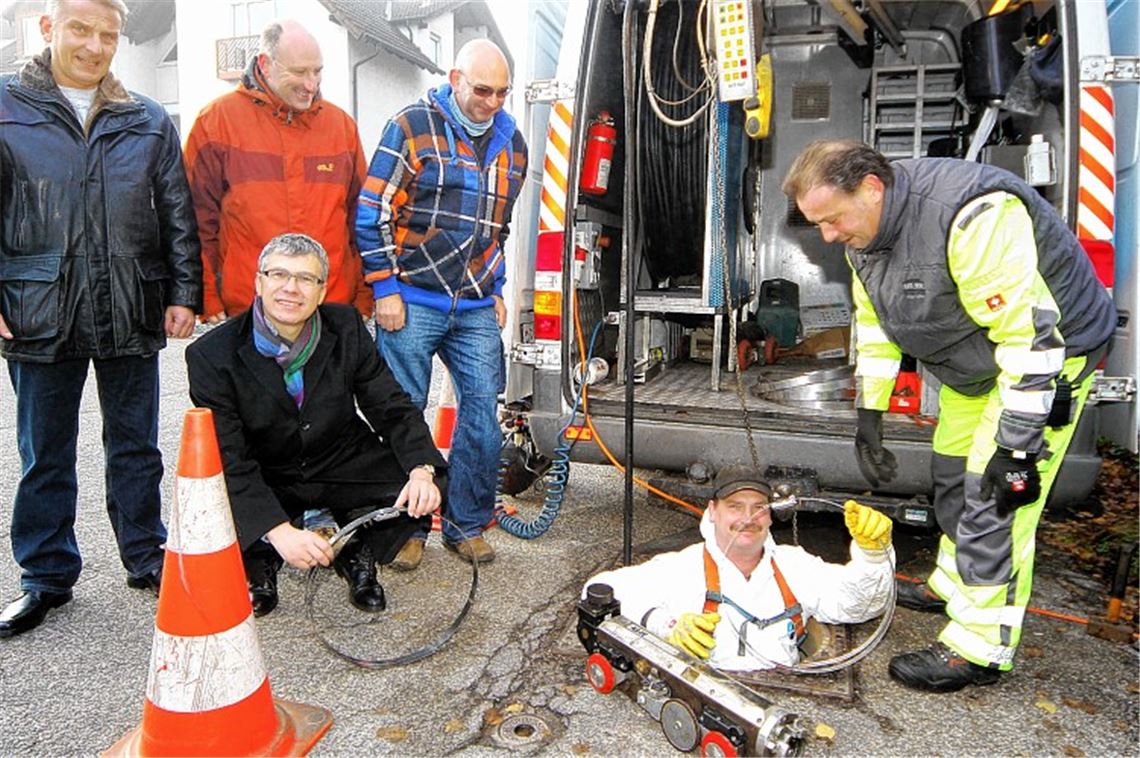 FastOpticom-Monteur Falko Angermann (unten) holt mit Unterstützung seines Kollegen Gerald Mußi Materialnachschub zur Bestückung des Roboters im Untergrund. Matthias Bosch, Uwe Pfisterer und Eckhard Buhl von den Stadtwerken sowie FastOpticom-Geschäftsführer Harry Aichele (davor) verfolgen das Geschehen.