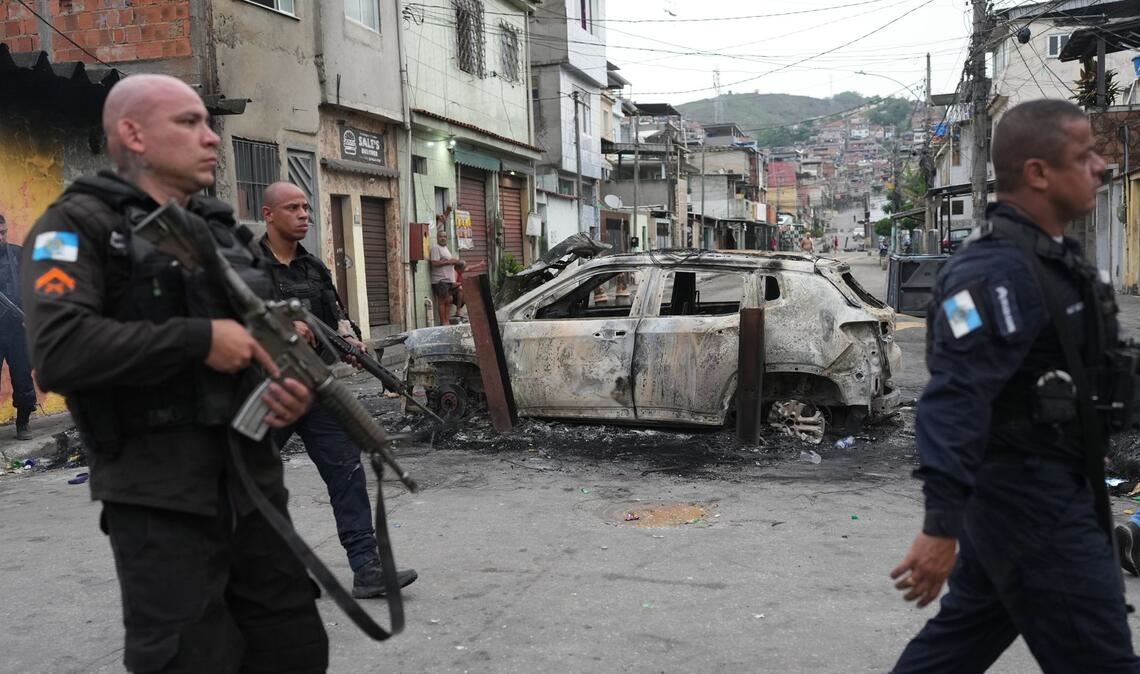 Favela „Complexo Alemao“: Polizisten gehen am Tag danach an einem verbrannten Auto vorbei.