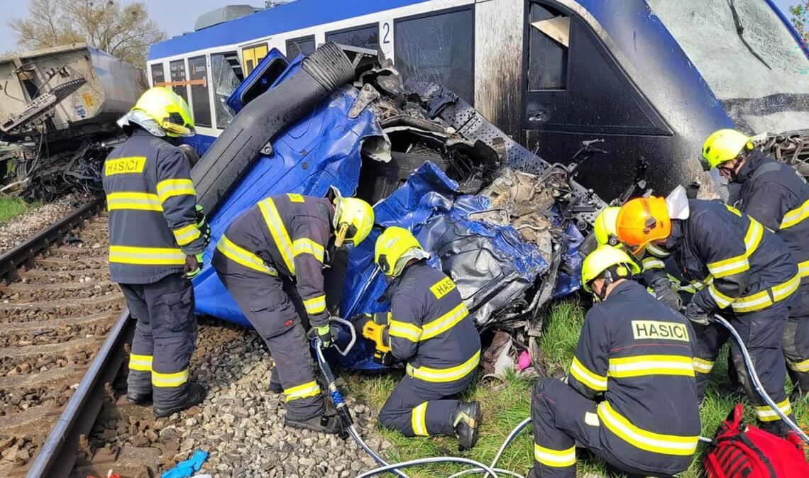 Feuerwehrleute arbeiten am Unglücksort, wo ein Personenzug und ein Lastwagen zusammengestoßen sind. Bei dem Unglück kam eine Person ums Leben, 21 Menschen wurden verletzt.