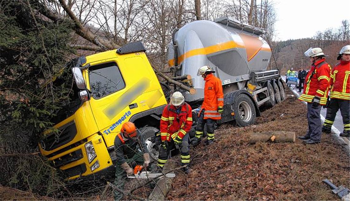 Feuerwehrleute aus Mönsheim beseitigen mit einer Motorsäge Teile einer Buche, gegen die der Silozug aus Ellmendingen prallte.