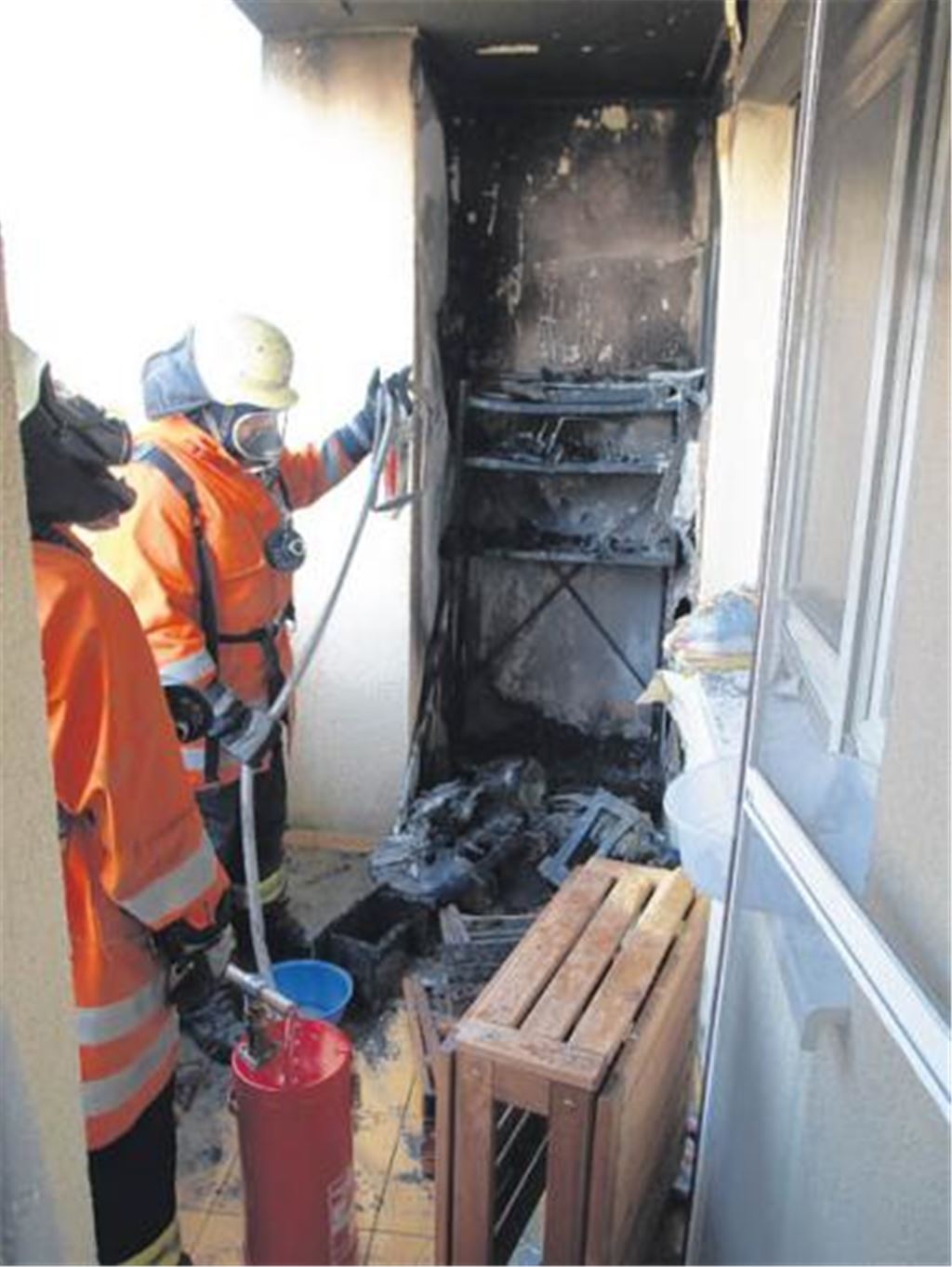 Feuerwehrleute sichern den Brandort. Im Hintergrund das völlig zerstörte Balkonregal.
Foto: Eier