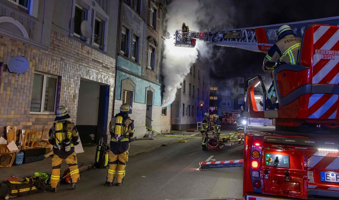 Feuerwehrleute sind u.a. mit einer Drehleiter damit beschäftigt, einen Brand in einem Wohnhaus in Essen zu bekämpfen.