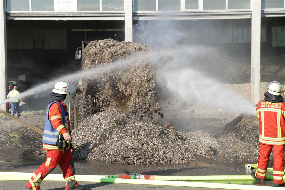 Feuerwehrmänner löschen das kokelnde Granulat ab. Foto: Eisemann