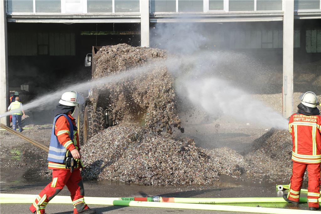 Feuerwehrmänner löschen das kokelnde Granulat ab. Foto: Eisemann