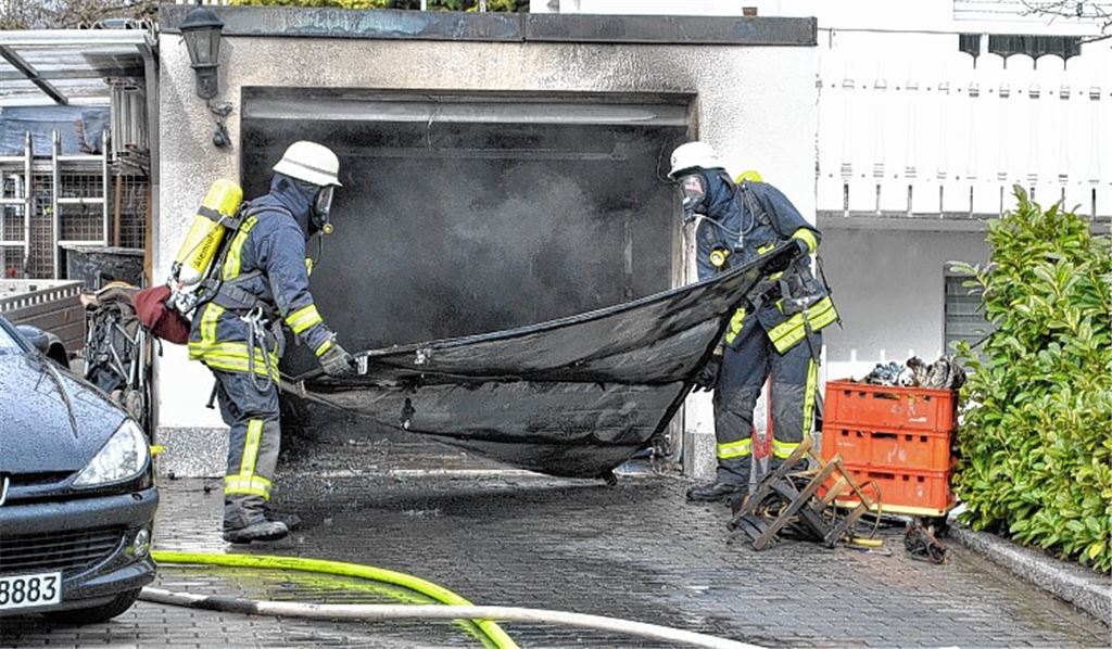 Feuerwehrmänner mit Atemschutz räumen die Garage aus. Im Einsatz waren mehr als 30 Kräfte der Abteilungen Illingen und Schützingen. Fotos: Stahlfeld