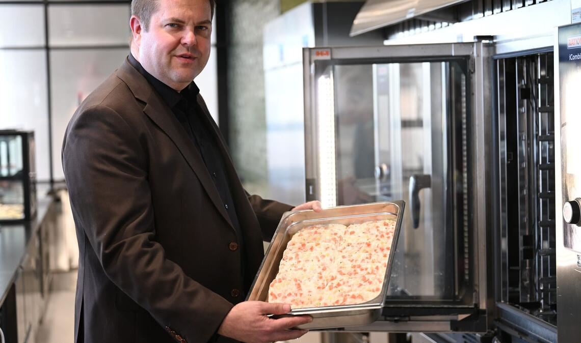 Firmenchef Jan-Peer Laabs hält im Betriebsrestaurant der Apetito-Zentrale eine Schale mit Lachs-Auflauf in der Hand.