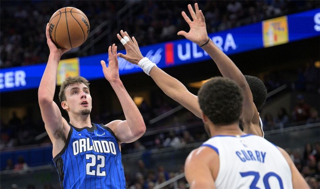 Franz Wagner (l/22) von Orlando Magic setzt Jordan Poole (hinten rechts) und Stephen Curry (30) von den Warriors zum Wurf an.