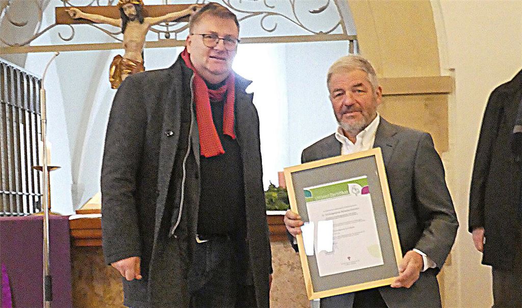 Friedrich Talmon (li.), Geschäftsführer des Evangelischen Bildungswerks, überreicht die Urkunde „Grüner Gockel“ an Günter Straub von der Andreasgemeinde. Foto: privat