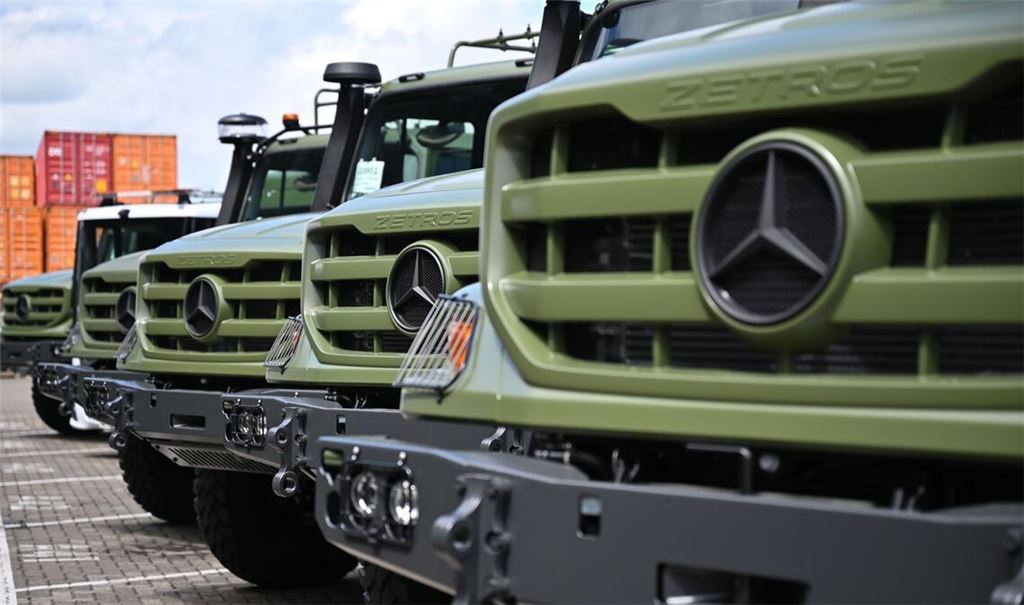 Für das Militär ausgestattete Laster vom Typ Zetros stehen vor einer Produktionshalle eines Lkw-Montagewerks von Mercedes-Benz Trucks.