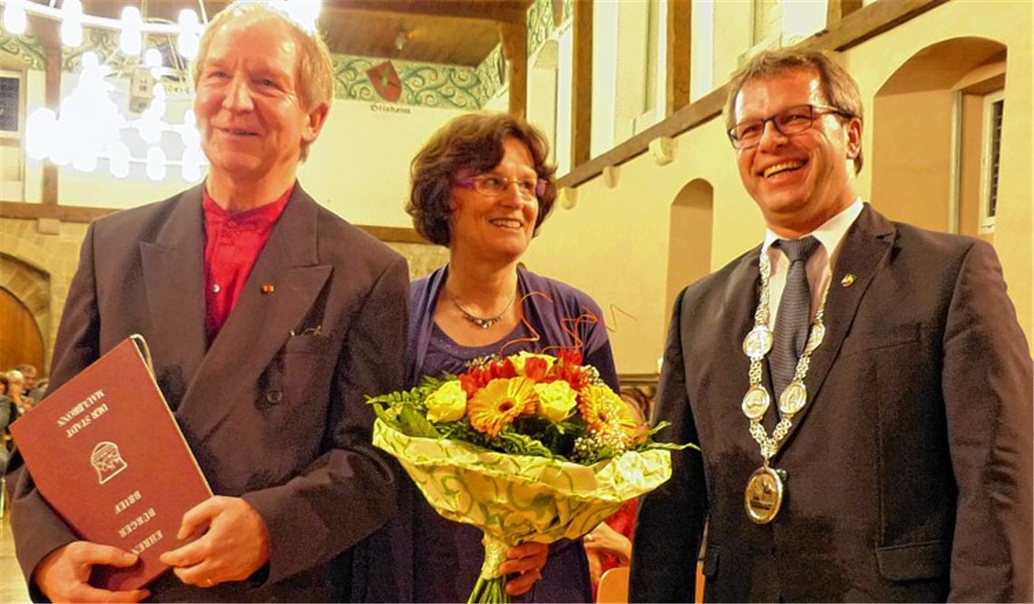 Für den Herrn die Ehrenbürger-Urkunde, für die Dame ein Blumengruß: Jürgen Budday, Erika Budday und Bürgermeister Andreas Felchle (re.) beim Empfang in der voll besetzten Stadthalle.