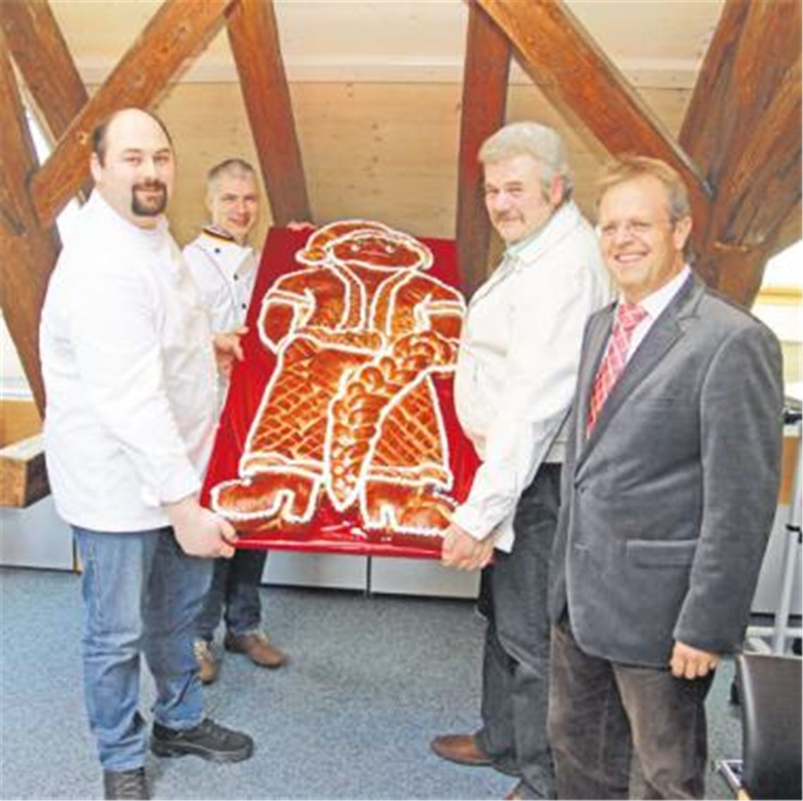 Für sein kommunalpolitisches Engagement zur Förderung des örtlichen Bäckerhandwerks erhält Bürgermeister Werner Henle (vorne re.) von den Bäckermeistern Matthias Burkert, Martin Reinhardt und Wolfgang Braun (v. li.) einen 25 Kilogramm schweren Dambedei. Die leckere Auszeichnung wird in diesem Jahr zum ersten Mal verliehen. Foto: Sadler