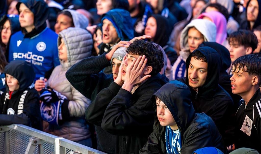 Fußball-Fans reagieren mit Entsetzen und Fassungslosigkeit auf die Tore der gegnerischen Mannschaft.