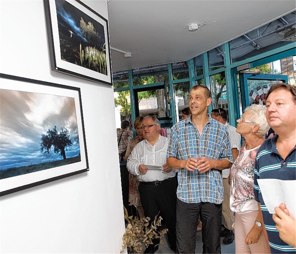 Gäste der Vernissage bewundern die Bilder von Volker Henkel (3. v. re.). Foto: Appich