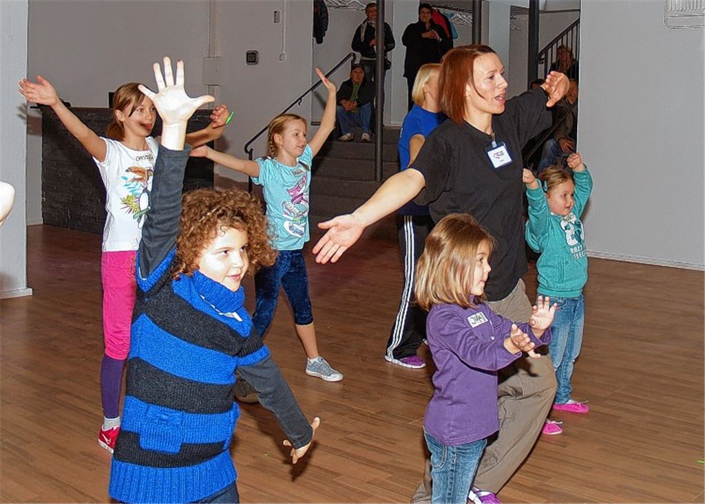 Gebannt beobachten die Kinder ihre Bewegungen im großen Spiegel. Von der Treppe aus schauen die Eltern mit Freude zu.