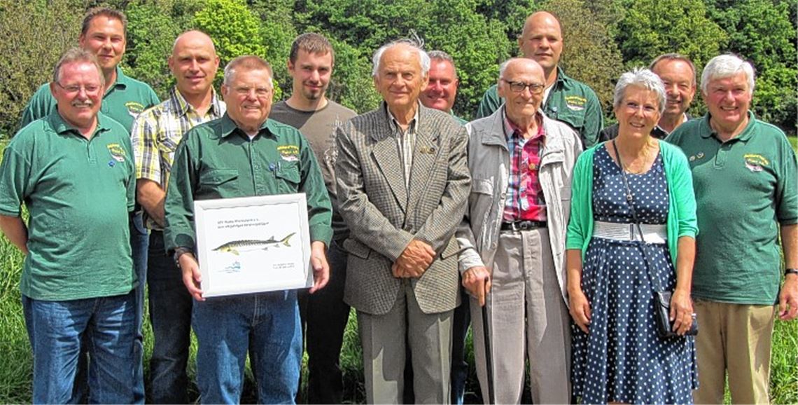 Geehrte Mitglieder des Angelsportvereins Platte. Vorsitzender Karl Heinz Dörfler (vorne, 2. v. li.) präsentiert das Präsent vom VfG, den Fisch des Jahres, zum 40-jährigen Vereinsbestehen. Foto: Rieger