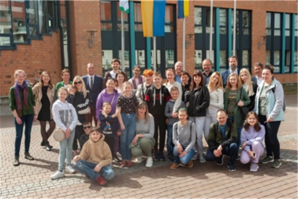 Geflüchtete aus der Ukraine, Vertreter von GHV, Mühlacker aktiv und MühlackerCard sowie der Stadt versammeln sich für ein Gruppenbild. Jeder Neuankömmling aus dem vom Krieg heimgesuchten Land soll in Mühlacker zwei Willkommens-Gutscheine im Wert von 25 Euro erhalten. Gewerbetreibende, Industrie und Handwerk sorgen für die Initialzündung des Projekts. Foto: Fotomoment