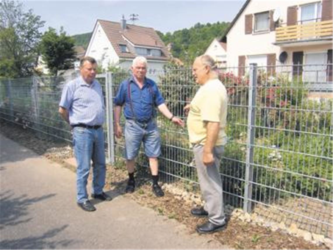 Gerhard Glüse (re.) vor seinem Garten. Er ärgert sich, weil er von der Stadt zur Kasse gebeten wird. Mit auf dem Bild: Jürgen Sauter (li.), dessen Tochter einen Streifen der alten B10 erwarb und ebenfalls von der Forderung des Abwasserbeitrags betroffen ist, sowie der Stadtrat Theo Bellon. Foto: Sadler