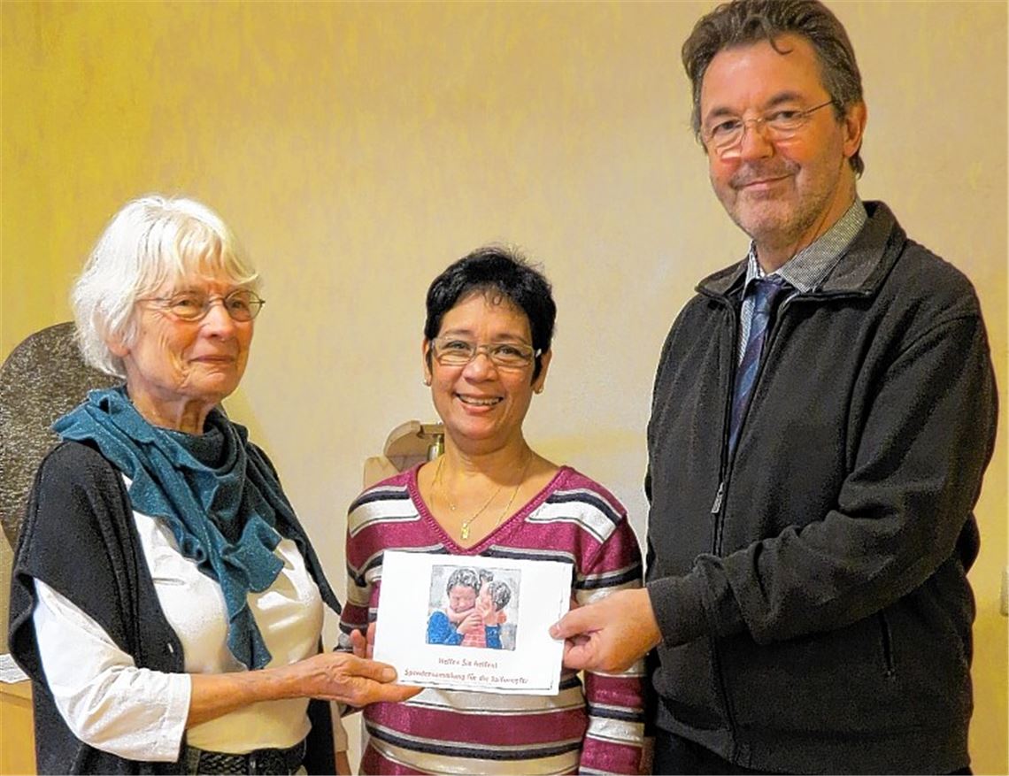 Geschäftsführer Thomas Kirst und Renate Dennerlein vom Bewohnerrat übergeben die Spende für die Opfer auf den Philippinen an Claudette Häfele (Mitte).