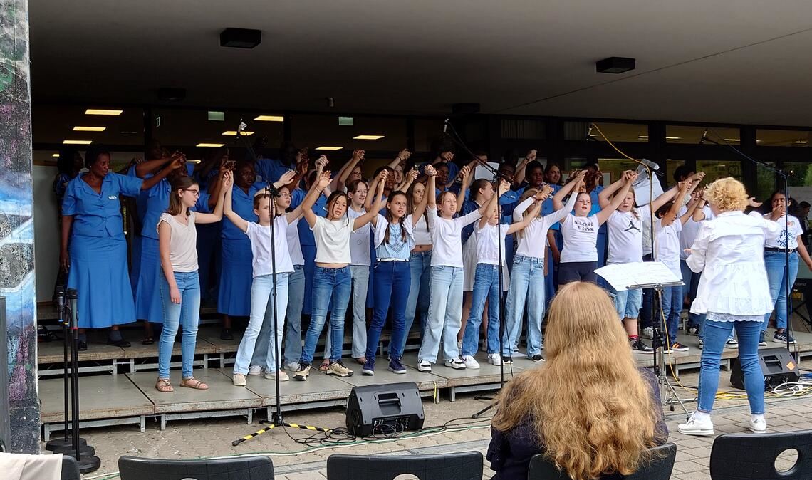 Geste der Verbundenheit zwischen THG-Schulchorsängerinnen und -sängern und den Gästen aus Tansania: „We are the world“ wird zu einem ganz besonderen Moment, der im Publikum von etlichen geschwenkten Handylampen begleitet wird. Foto: privat