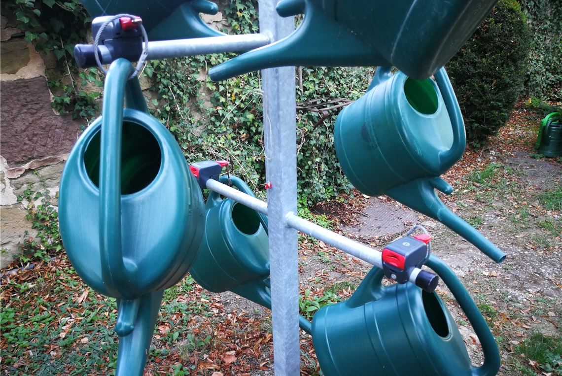 Pfandsystem gegen Gießkannen-Klau Gießkannen an einer Pfandstation auf dem Friedhof Lienzingen.privat