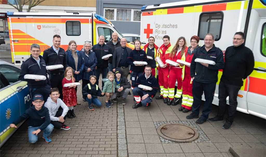 Gisela Oser (4. v. li. ) und Winfried Abicht (7. v. li.) von der Verkehrswacht übergeben Christstollen an Einsatzkräfte von DRK, Feuerwehr, Malteser und Polizei. Foto: Fotomoment