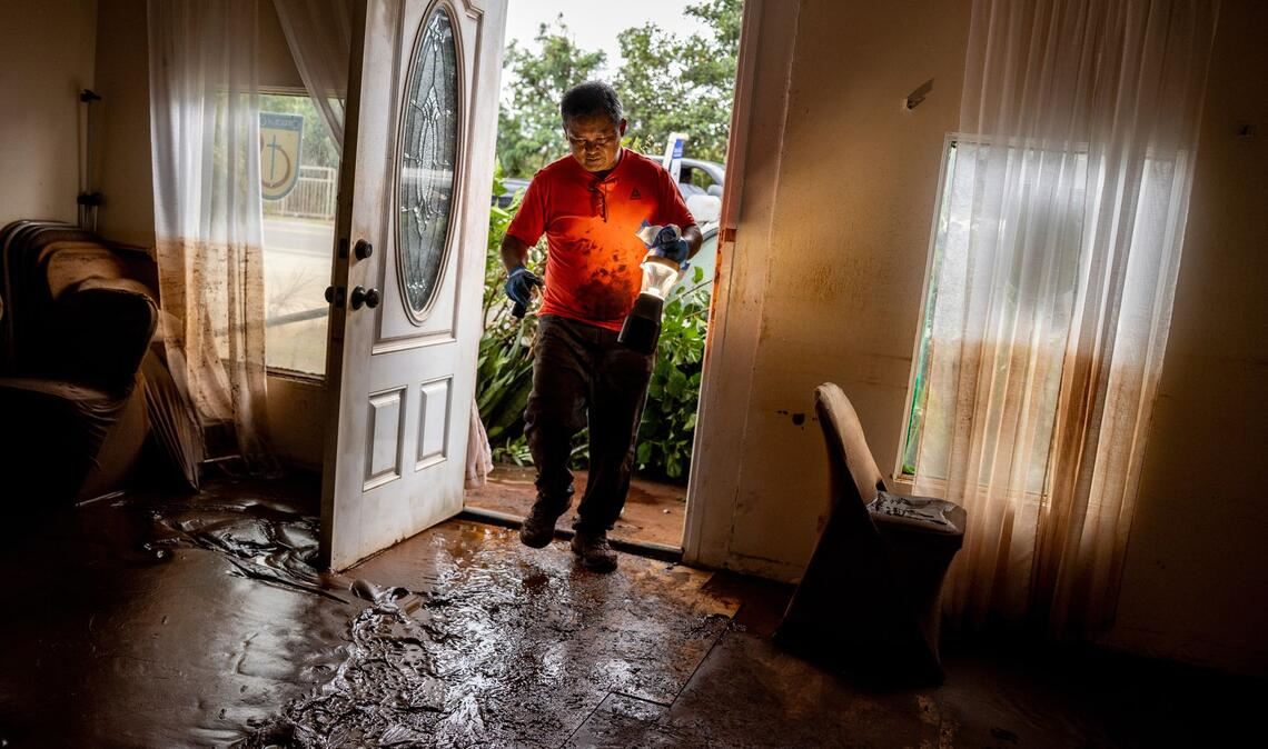 Glenn Duquez, stellvertretender Pastor der Church of God Jesus is Alive Fellowship, trägt eine Lampe in das schlammdurchtränkte Kirchengebäude, um nach der Flut aufzuräumen.