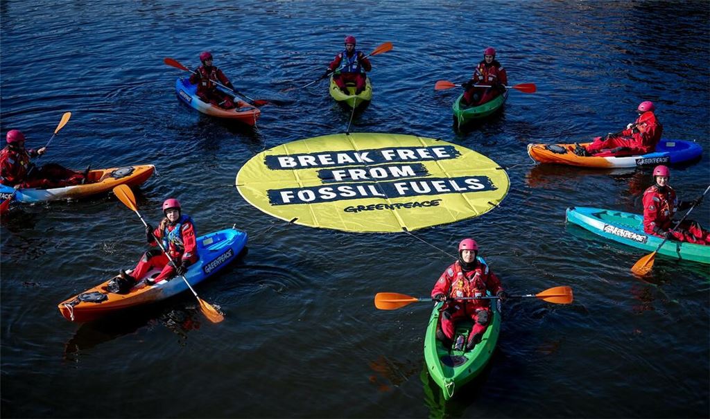 Greenpeace fordert bei einer Aktion am Veranstaltungsort die Abkehr von fossilen Energien.