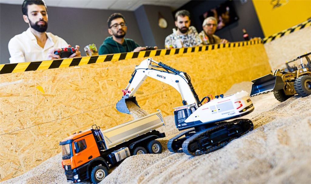 Gründer Siymo Othman (links) steuert mit Freunden kleine Bagger, Radlader und Lastwagen in seinem neu eröffneten Bagger-Café. Es soll das erste dieser Art in Deutschland sein.