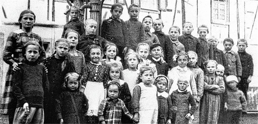 Gruppenbild: Die Kinder der Volksschulklassen 1 bis 8 vor dem Brunnen in der Zwerchstraße um 1918.