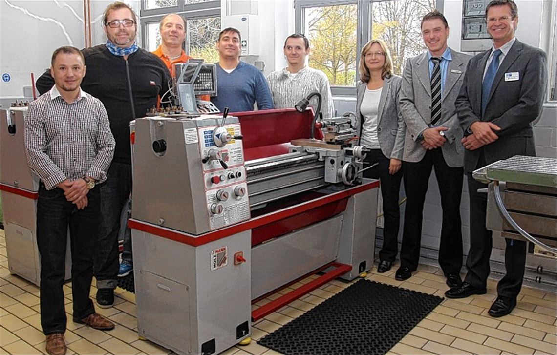 Gruppenbild an der Drehmaschine: Die Teilnehmer eines Qualifizierungsprojekts Michael Naam (v.li.), Paolo De Giglio, Robert Vadlja-Kovac, Kirill Frank und Jürgen Riss können sich über IHK- beziehungsweise hiwentis-Zertifikate freuen. Mit auf dem Bild: hiwentis-Geschäftsführerin Gabriele Hildwein, Thorsten Först vom Jobcenter Pforzheim (2.v.re.) und Gerold Mönch von der IHK. Foto: Sadler