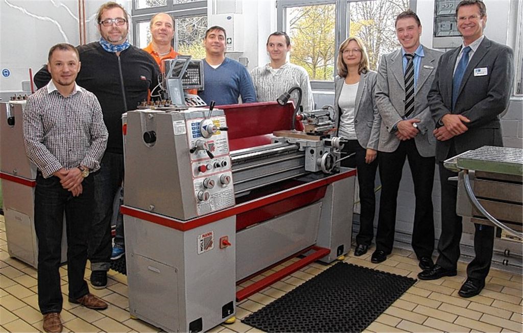 Gruppenbild an der Drehmaschine: Die Teilnehmer eines Qualifizierungsprojekts Michael Naam (v.li.), Paolo De Giglio, Robert Vadlja-Kovac, Kirill Frank und Jürgen Riss können sich über IHK- beziehungsweise hiwentis-Zertifikate freuen. Mit auf dem Bild: hiwentis-Geschäftsführerin Gabriele Hildwein, Thorsten Först vom Jobcenter Pforzheim (2.v.re.) und Gerold Mönch von der IHK. Foto: Sadler