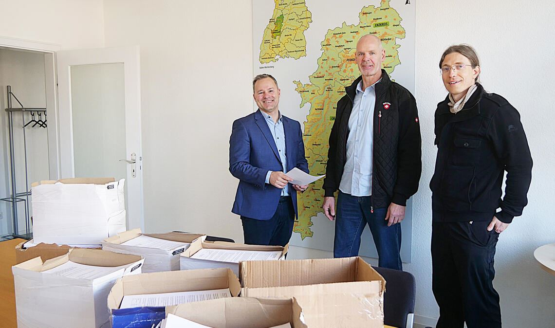Gunnar Minstedt (Mitte) und Daniel Mesitschek (re.) übergeben an Regionalverbandsdirektor Sascha Klein rund 12000 Stellungnahmen aus Großglattbach zur Planung von Windvorranggebieten im Gebiet rund um den Mühlacker Stadtteil. Foto: Friedrich