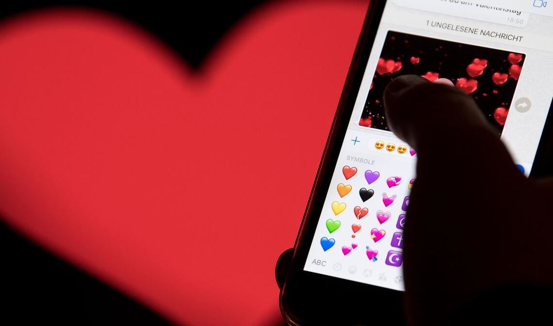 Hand aufs Handy - das rote Herz zählt zu den beliebtesten Emojis. (Archivbild)