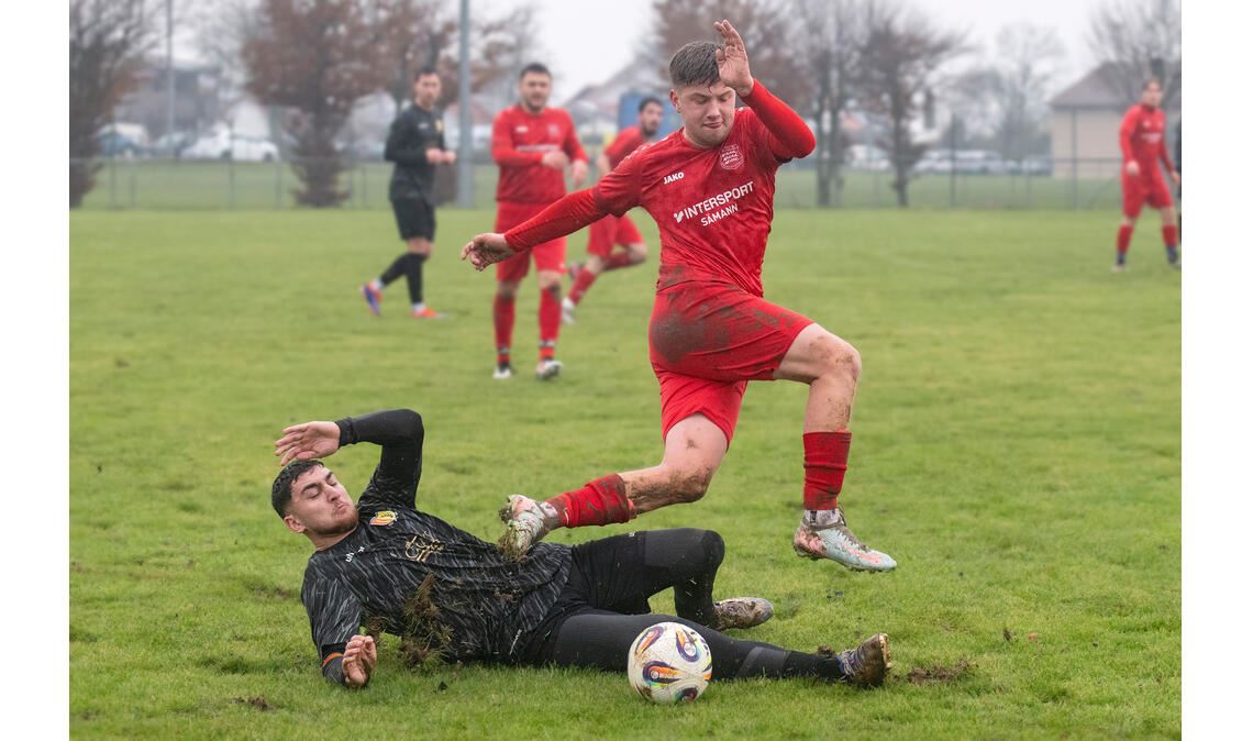 Hart umkämpft ist die Partie zwischen dem TSV Großglattbach (rote Trikots) und Enzweihingen auf dem rutschigen Rasen. Foto: Fotomoment.