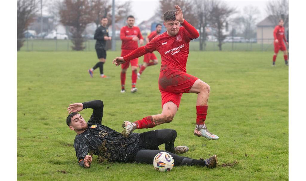Hart umkämpft ist die Partie zwischen dem TSV Großglattbach (rote Trikots) und Enzweihingen auf dem rutschigen Rasen. Foto: Fotomoment.