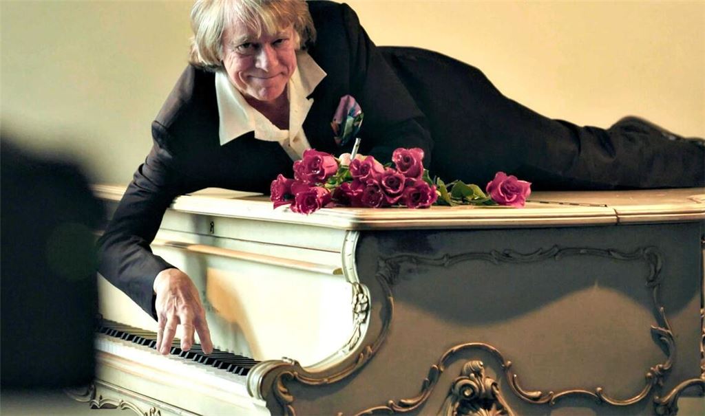 Helge Schneider liegt auf einem Klavier in einer Szene des Films "Helge Schneider - The Klimperclown", der nun in der Mediathek zu sehen ist und am Mittwoch, 20.8., im Ersten gezeigt wird.