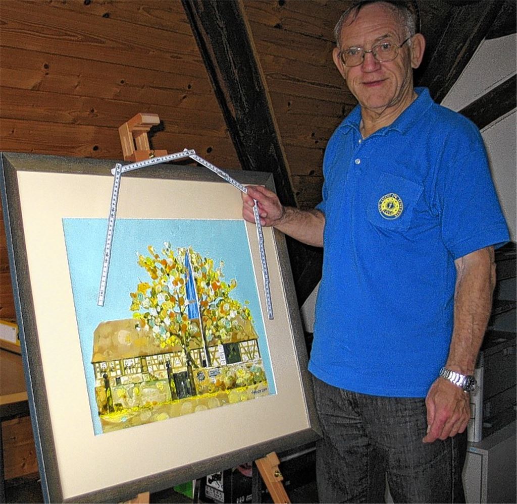 Herbert Temme mit Meterstab und Gemälde – zwei Finanzierungsbausteinen. Ein großes Schild hat die Besucher des Maifests am Henri-Arnaud-Haus über die anstehenden Arbeiten informiert.